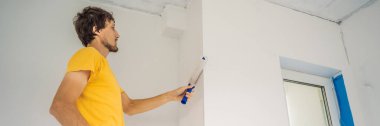 Bir erkek boyacı boyacı boya ve boya silindiriyle duvar astar. DIY BANNER, BÜYÜK