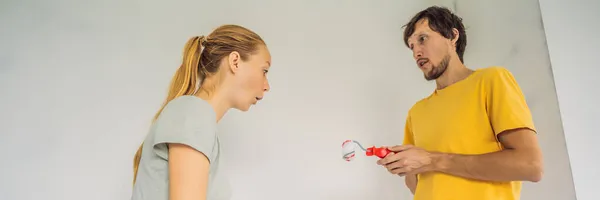 BANNER, LONG FORMAT A man and a woman with rollers for painting the walls. A man with a very small bolster, symbolizing a small penis. renovation diy paint couple in new home painting wall — Stok fotoğraf