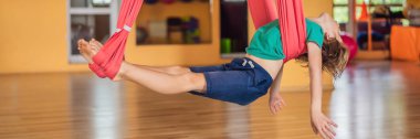 Spor salonunda hava yogası yapan küçük bir çocuk. Yaşam tarzı. Çocuklar için yoga konsepti BANNER, uzun format