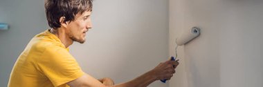 Bir erkek boyacı boyacı boya ve boya silindiriyle duvar astar. DIY BANNER, BÜYÜK