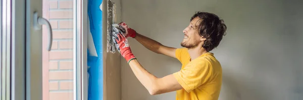 バンナー、ロングフォーマットプラスターホーム改善アパートの壁の充填に取り組んでパテナイフで手作り労働者 — ストック写真