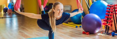 Genç ve güzel bir kadın spor salonunda hava yogası yapıyor. HAYAT BANNER, BÖLÜM