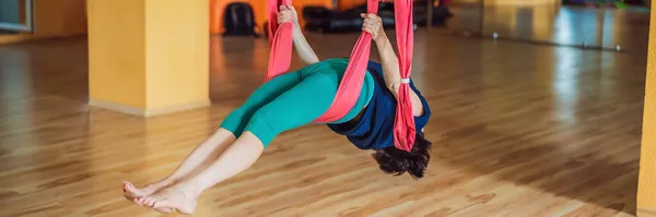 Senior mature woman practices anti-gravity yoga with a hammock in a studio. Lifestyle BANNER, LONG FORMAT — Stock Photo, Image