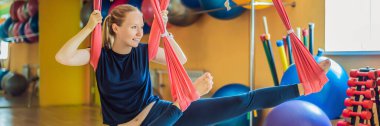 Genç ve güzel bir kadın spor salonunda hava yogası yapıyor. HAYAT BANNER, BÖLÜM