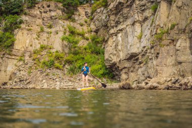 Denizde Dik Yüzen Genç Kadınlar Eğleniyor. - Süper. Kızıl saçlı kız kayaların yanındaki sörf tahtasında çalışıyor.