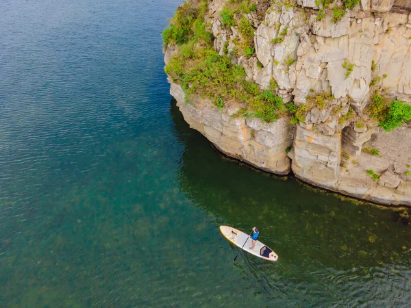 Junge Frauen haben Spaß beim Stand Up Paddling im Meer. SUP. Mädchen mit roten Haaren trainiert auf Paddelbrett in der Nähe der Felsen — Stockfoto