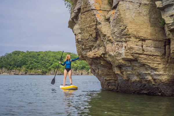 Młode kobiety mają zabawy Stand Up Wiosłując w morzu. SUP. Rude włosy dziewczyna Trening na Paddle Board w pobliżu skał — Zdjęcie stockowe