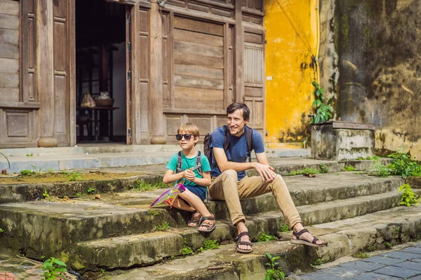 Táta a syn cestovatelé na pozadí Hoi An starobylé město, Vietnam. Vietnam se opět otevírá turistům po karanténě Coronovirus COVID 19 — Stock fotografie