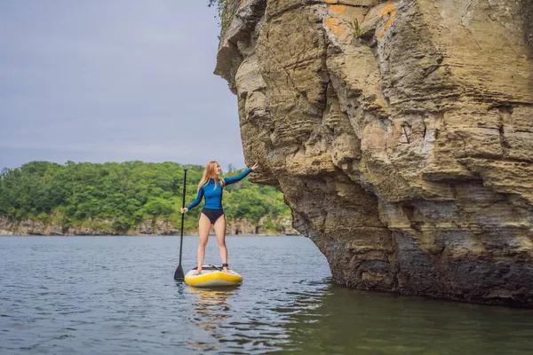 Young women Having Fun Stand Up Paddling in the sea. SUP. Red hair girl Training on Paddle Board near the rocks — Stock Photo, Image