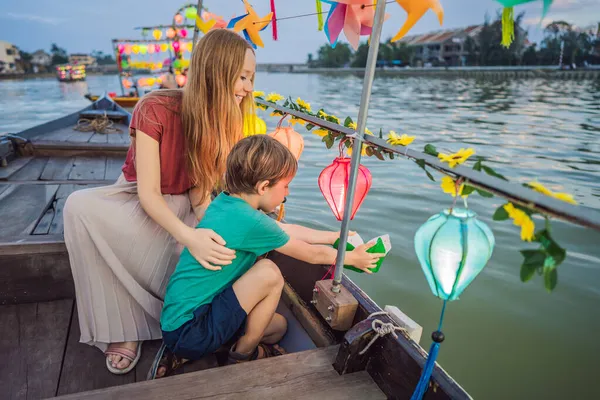 Família feliz Mãe e filho de viajantes montam um barco nacional no fundo de Hoi Uma cidade antiga, Vietnã. Vietnã abre para turistas novamente após quarentena Coronovirus COVID 19 — Fotografia de Stock