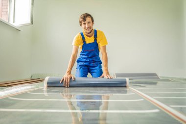 Usta odaya film döşemesi kuruyor. Zemin ısıtma kurulumu