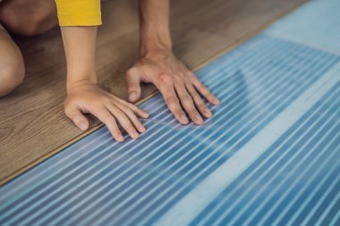 Ahşap zemin, sıcak bir film zeminine kaplanmış. Evdeki rahatlık. Sıcak zemin konsepti. Evde ve dairede ısıtma var.