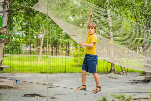 Kleiner Junge in einem Seilpark. Aktive körperliche Erholung des Kindes an der frischen Luft im Park. Ausbildung für Kinder — Stockfoto