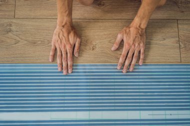 Adam sıcak film katta yeni ahşap Laminat parke yükleme. Kızılötesi yerden ısıtma sistemi Laminat zemin altında