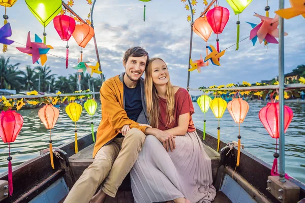 Glada par resenärer rida en nationell båt på bakgrund av Hoi An antika staden, Vietnam. Vietnam öppnar för turister igen efter karantän Coronovirus COVID 19 — Stockfoto