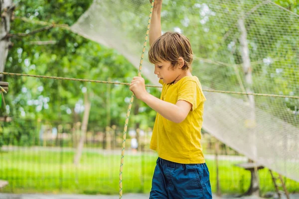 Το αγοράκι σε ένα πάρκο με σχοινιά. Ενεργός φυσική αναψυχή του παιδιού στον καθαρό αέρα στο πάρκο. Εκπαίδευση για παιδιά — Φωτογραφία Αρχείου