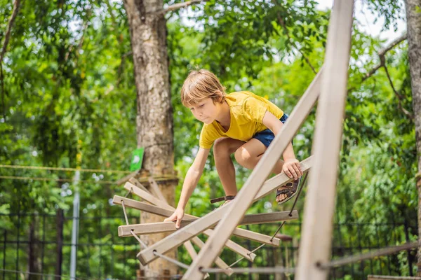 Kisfiú egy kötélen parkban. Aktív testi kikapcsolódás a gyermek friss levegőn a parkban. Gyermekképzés — Stock Fotó