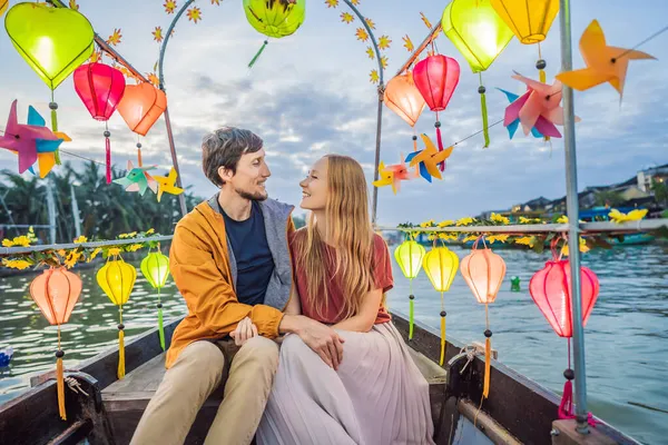 Happy couple of travelers ride a national boat on background of Hoi An ancient town, Vietnam. Vietnam opent weer voor toeristen na quarantaine Coronovirus COVID 19 — Stockfoto