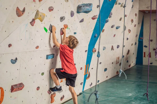 Chłopiec przy ścianie wspinaczkowej bez kasku, niebezpieczeństwo przy ścianie wspinaczkowej — Zdjęcie stockowe