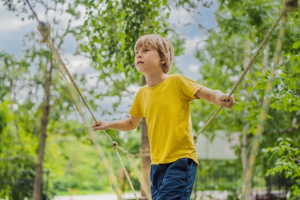 Kleine jongen in een touwenpark. Actieve fysieke recreatie van het kind in de frisse lucht in het park. Opleiding voor kinderen — Stockfoto