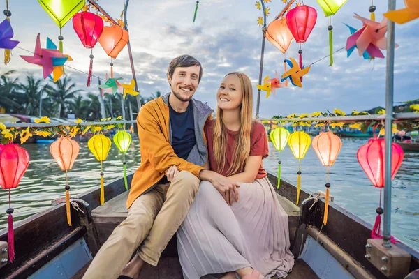 Glada par resenärer rida en nationell båt på bakgrund av Hoi An antika staden, Vietnam. Vietnam öppnar för turister igen efter karantän Coronovirus COVID 19 — Stockfoto