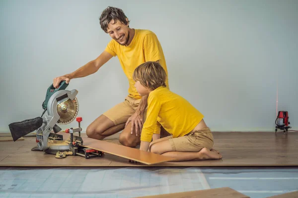 Padre e figlio l'installazione di nuovi pavimenti in laminato di legno su un pavimento caldo pellicola. sistema di riscaldamento a pavimento a infrarossi sotto pavimento in laminato — Foto Stock