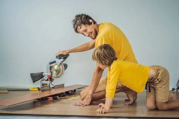 Padre e figlio l'installazione di nuovi pavimenti in laminato di legno su un pavimento caldo pellicola. sistema di riscaldamento a pavimento a infrarossi sotto pavimento in laminato — Foto Stock