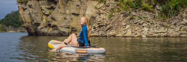 BANNER, LONGO FORMATO Jovens mulheres se divertindo se levantam remo no mar. SUP. Menina de cabelo vermelho Treinamento em Paddle Board perto das rochas — Fotografia de Stock