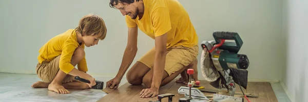 BANNER, FORMATO LUNGO Padre e figlio l'installazione di nuovi pavimenti in laminato di legno su un pavimento caldo pellicola. Sistema di riscaldamento a pavimento a infrarossi sotto pavimento in laminato — Foto Stock