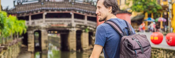 BANNER, Hoi An 'daki Güzel Japon Köprüsü' nün arka planında eski bir turist. Vietnam. Vietnam, Coronovirus COVID 19 karantinasından sonra turistlere tekrar açıldı — Stok fotoğraf