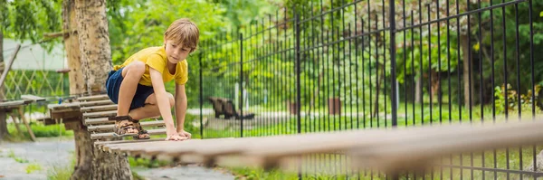 Un niño en un parque de cuerdas. Recreación física activa del niño al aire libre en el parque. Formación para niños BANNER, FORMATO LARGO —  Fotos de Stock