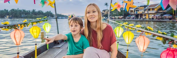 BANNER, FORMATO LARGO Familia feliz Madre e hijo de los viajeros montan un barco nacional en el fondo de Hoi Una antigua ciudad, Vietnam. Vietnam se abre de nuevo a los turistas después de la cuarentena Coronovirus COVID 19 —  Fotos de Stock