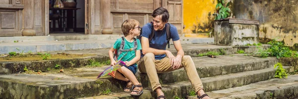 BANNER, DLOUHÝ FORMÁT Otec a syn cestovatelé na pozadí Hoi An starobylé město, Vietnam. Vietnam se opět otevírá turistům po karanténě Coronovirus COVID 19 — Stock fotografie