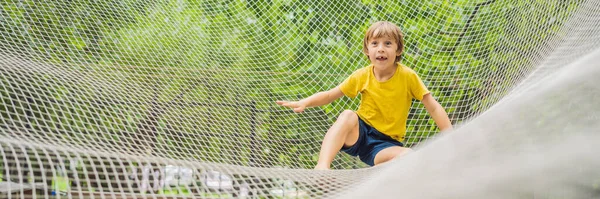 BANNER, LONG FORMAT practice nets playground. boy plays in the playground shielded with a protective safety net. concept of children on line, kid in social networks. blurred background, blurred motion — Stock Photo, Image