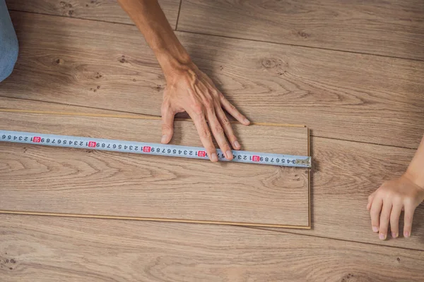 Homem instalando novo piso laminado de madeira em um piso filme quente. sistema de aquecimento de piso infravermelho sob piso laminado — Fotografia de Stock