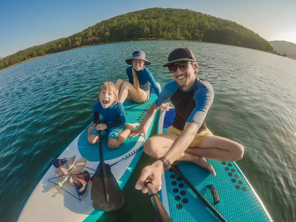 Família feliz de três, pai, mãe e filho, desfrutando de pé remando durante as férias de verão — Fotografia de Stock