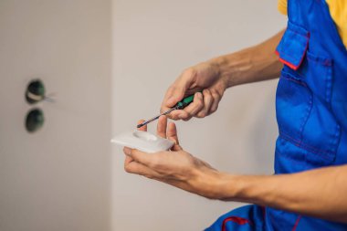 Usta elektrikçi eve bir soket takıyor.