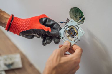 Usta elektrikçi eve bir soket takıyor.