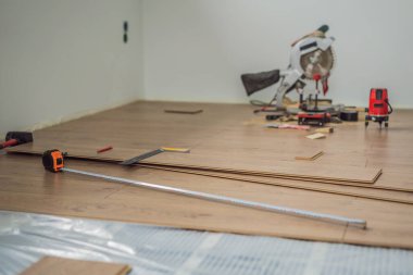 Sıcak bir film zeminine yeni ahşap döşeme döşeniyor. Kızıl ötesi ısıtma sistemi lamine zemin altında