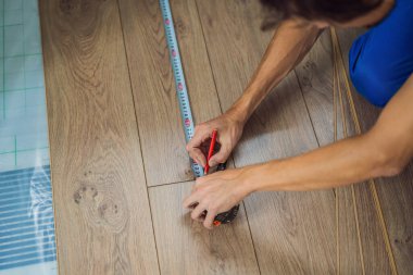 Adam sıcak film katta yeni ahşap Laminat parke yükleme. Kızılötesi yerden ısıtma sistemi Laminat zemin altında