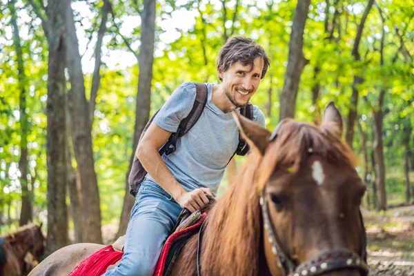 Bel homme monter sur le cheval noir dans la forêt verte — Photo