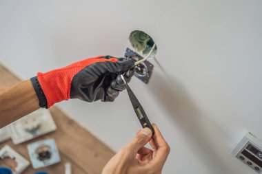 Usta elektrikçi eve bir soket takıyor.