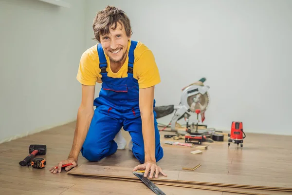 Homem instalando novo piso laminado de madeira em um piso filme quente. sistema de aquecimento de piso infravermelho sob piso laminado — Fotografia de Stock