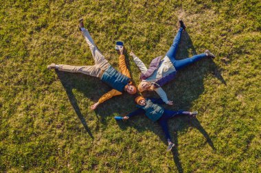 Aile manzarası. Çimlerin üzerinde yatıyordu. Güneşli bir gün. Yeşil doğada birlikte. Hava görüntüleme Drone fotoğrafçılığı