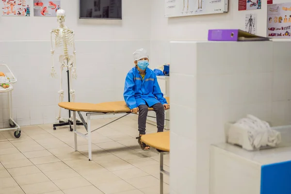 Мальчик играет в доктора в униформе в больнице интерьера — стоковое фото