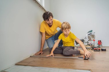 Baba ve oğul yeni ahşap Laminat parke sıcak film katta yükleme. Kızılötesi yerden ısıtma sistemi Laminat zemin altında