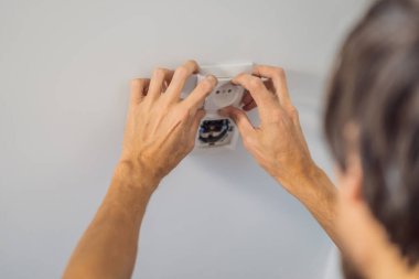 Usta elektrikçi eve bir soket takıyor.