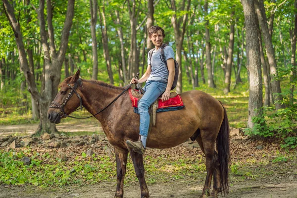 Bel homme monter sur le cheval noir dans la forêt verte — Photo