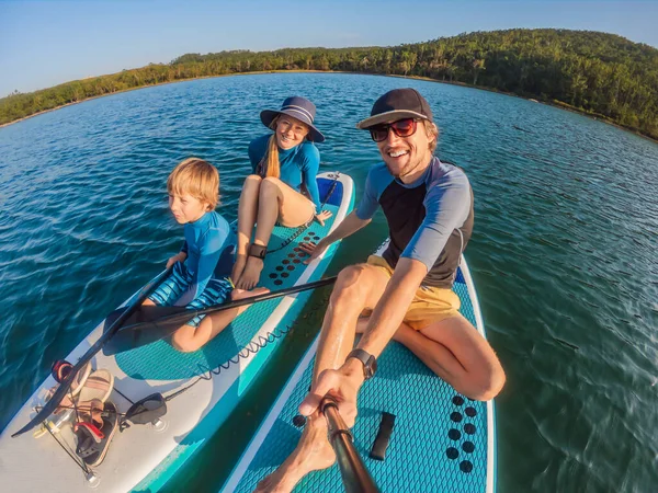 Happy family of three, dad, mom and son, enjoying stand up paddling during summer vacation — Stock Photo, Image