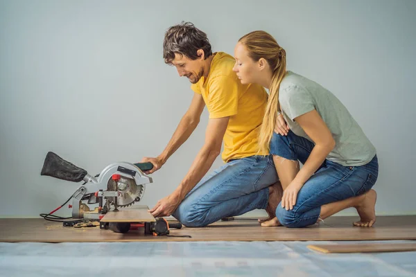 Coppia sposata l'installazione di nuovi pavimenti in laminato di legno su un pavimento caldo pellicola. Sistema di riscaldamento a pavimento a infrarossi sotto pavimento in laminato — Foto Stock